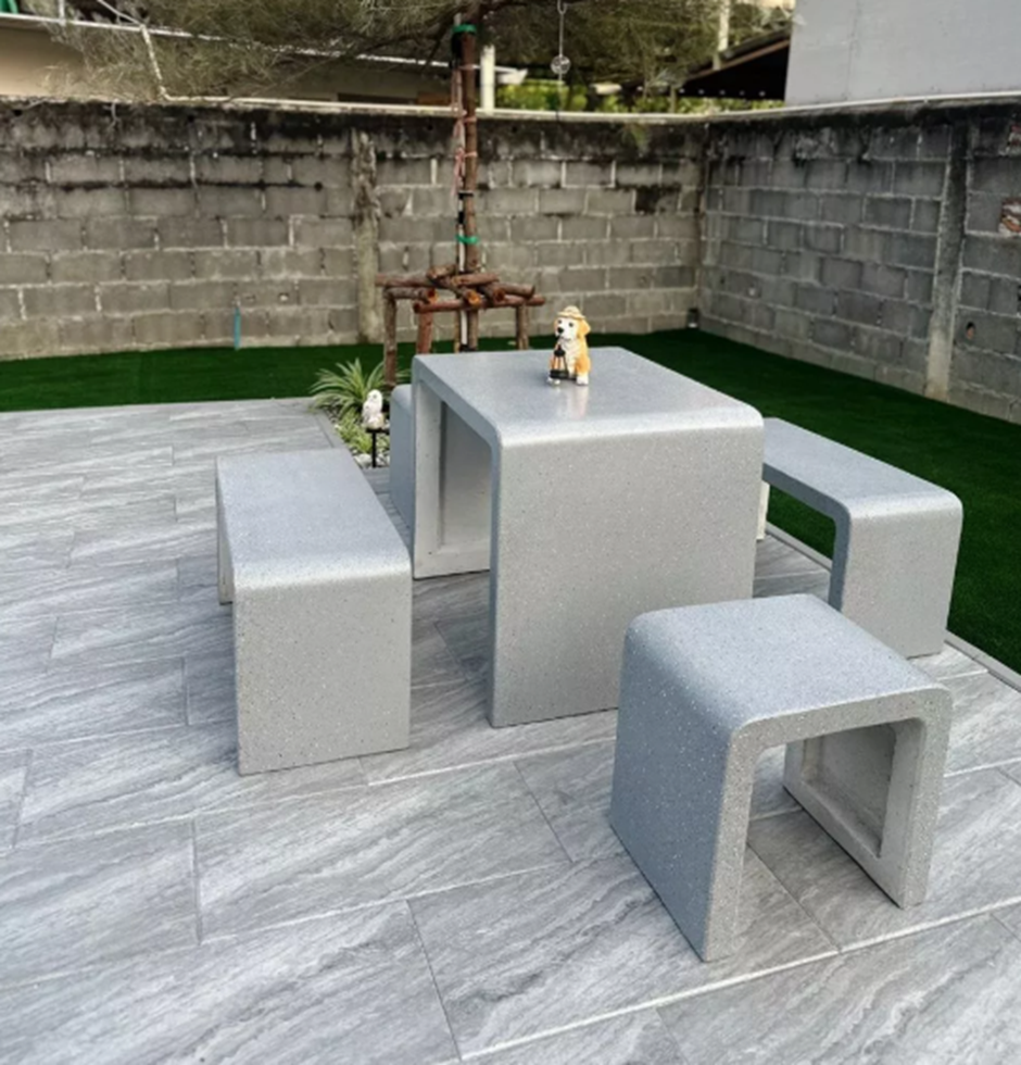 โต๊ะปูนดิบสไตล์ลอฟท์สีเทาอ่อนเกล็ด พร้อมม้านั่ง วางบนพื้นกระเบื้องในสวน